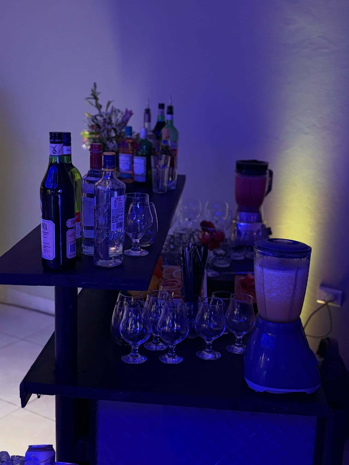 Botellas, copas y licuadoras con jugo listos en la barra de una fiesta
