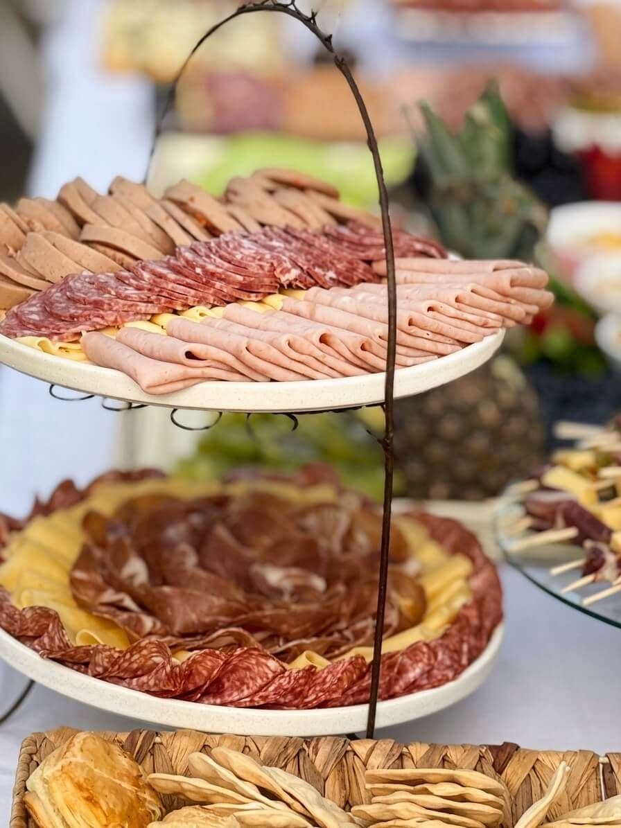 Bandeja de dos pisos con salame, jamón, mortadela y quesos, y galletas en una canasta